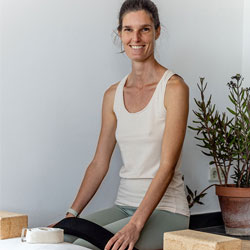 rianne sitting surrounded by yoga props smiling